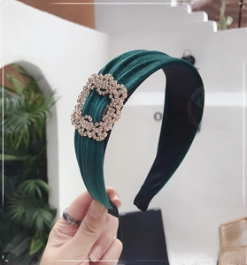 Detail of dark green velvet headband featuring a large sparkling rectangular rhinestone buckle