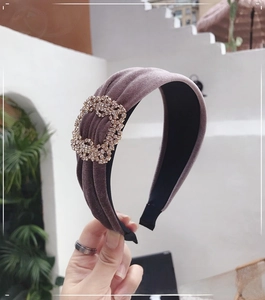 Detail of velvet headband featuring a large square rhinestone buckle in grey-purple hue
