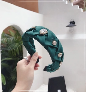 Detail of dark green woven headband with crystal rhinestones and pleated texture
