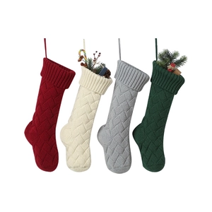 Close-up of four knitted Christmas stockings with cable patterns and festive gift fillers