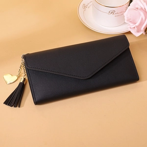 Detail of black long envelope wallet with gold heart pendant and elegant leather texture