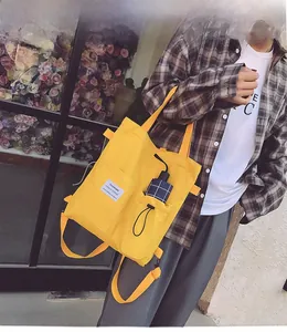 Macro detail of bright yellow canvas bag showing front pocket and fashion textile label