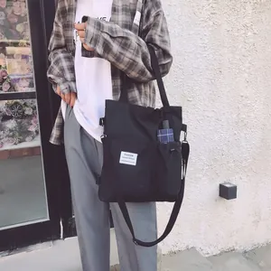 Detail der schwarzen Canvas-Tragetasche mit Modeetikett und seitlicher Kordelzugtasche
