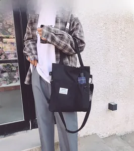 Detail of black canvas tote bag showing fashion label and side drawstring pocket