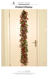 Detailed view of Christmas garland with red berries, pine cones and green leaves on a white door