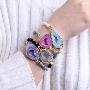 Set of four natural druzy agate beaded bracelets with gold trim on a female model's wrist