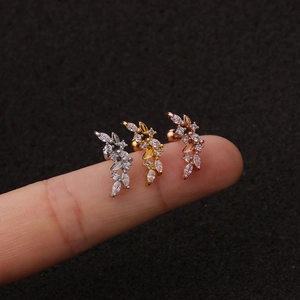 Macro di tre orecchini a lobo con foglie di zircone in argento, oro e oro rosa su dito