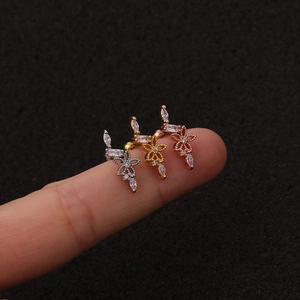 Vista macro di tre orecchini a fiore in argento, oro e oro rosa sulla punta di un dito