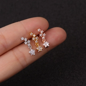 Macro shot of silver, gold, and rose gold star earrings with zircon inlay held by a hand