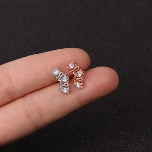 Pentagram zircon earrings in silver and rose gold shown on fingertip for size