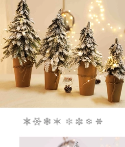 Detailed view of four mini flocked Christmas trees with LED lights and snow-covered branches