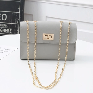 Detail of grey PU leather crossbody bag featuring a gold metal turn-lock and chain strap