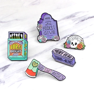 Five-piece set of Gothic enamel pins with skull, coffin, and axe motifs on marble surface