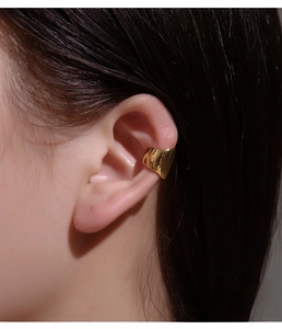 Close-up of polished gold-finished wide geometric ear cuff on a model ear