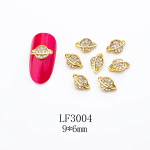 Golden Saturn shaped nail charm LF3004 with white rhinestones and pink nail display