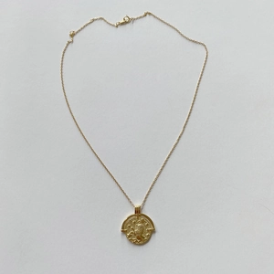 Detailed shot of golden coin necklace with embossed celestial lion pendant and thin chain