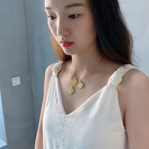 Detailed view of triple-layered gold coin necklace with baroque portrait embossed pendant