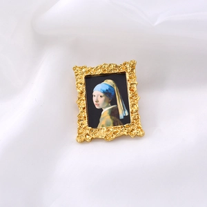 Detail of baroque gold metal brooch featuring Girl with a Pearl Earring on white silk