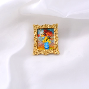 Detail of vintage gold-framed brooch with miniature oil painting on white fabric