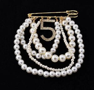 Macro shot of French vintage brooch with pearls and diamond-encrusted number five pendant