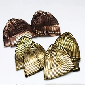 Metallic shiny knitted beanies in gold and bronze finish stacked on white background