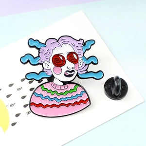 Detail showing cartoon girl enamel pin with purple hair and red glasses on display card
