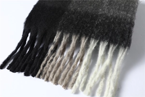 Détail des franges sur une écharpe douce en dégradé de noir à gris avec effet cachemire