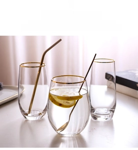 Detail of lead-free glass cup with handcrafted gold rim and metal straw for water