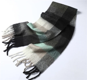 Détail d'une écharpe à carreaux avec franges en noir, gris, blanc et vert menthe