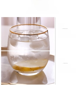 Detail view of round gold rim and thick base of lead-free glass cup with ice