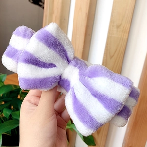 Close-up of purple and white striped plush bow headband for washing face and makeup