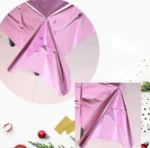 Close-up of shiny pink metallic foil tablecloth with festive Christmas party decorations