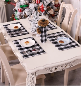 Close-up of black and white plaid placemats and wine bottle cover on a festive table