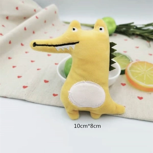 Close-up of yellow plush crocodile doll decoration with heart-patterned background