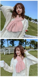 Close-up of a soft pink knitted scarf styled in a cross-knot on a model in sunlight