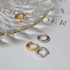 Close-up of gold and silver minimalist huggie hoop earrings on a glass tray