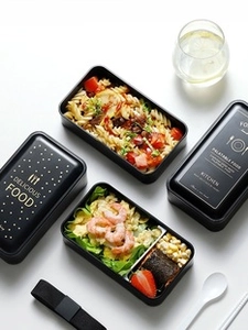 Flat lay of black double-layer lunch box set with gold patterns, cutlery and elastic band