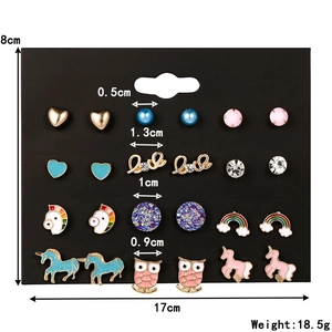 Set di 12 paia di orecchini a lobo con animali, frutta e forme colorate su carta nera