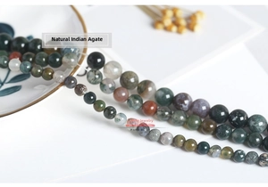 Macro detail of natural Indian Agate round beads in earthy tones on a white ceramic tray