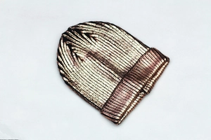 Macro detail of rose gold knit beanie showing metallic texture and ribbed cuff design