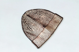 Macro shot of metallic bronze knitted beanie showing detailed texture and reflective finish