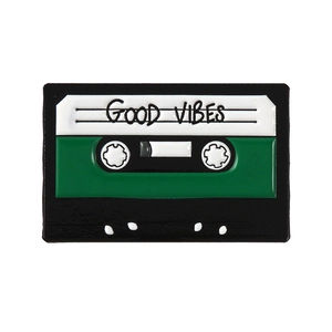 Spilla smaltata stile cassetta vintage con testo 'Good Vibes' e design musicale
