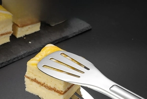 Macro d'une pince en acier inoxydable avec design creux saisissant un gâteau
