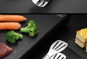 Détail d'une pince inox saisissant de la viande sur un gril électrique noir
