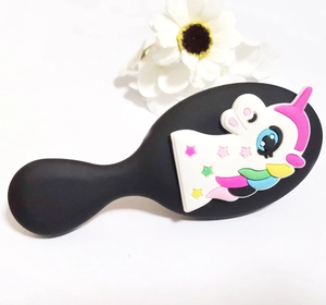 Detail of black paddle brush featuring a cute white cartoon unicorn with colorful stars