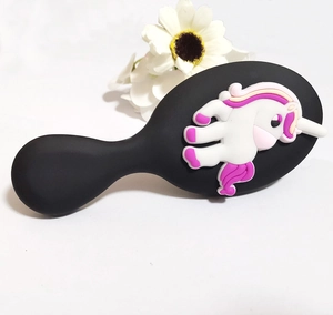 Detail of a black hairbrush handle featuring a cute white unicorn with colorful mane
