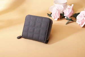 Detail of dark grey quilted leather wallet with gold zipper and litchi texture