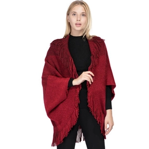Detail of red knit poncho with elegant tassels showing warm acrylic texture and drape