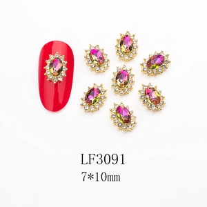 Macro view of oval iridescent crystal nail charms with small rhinestones and gold base
