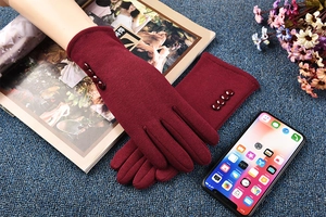 Detail of burgundy thermal gloves with decorative buttons and touchscreen fingertips